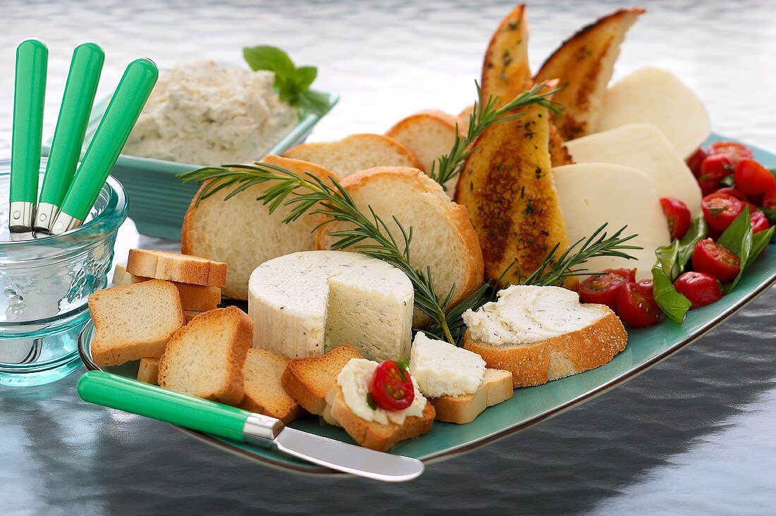 Platter with slices of white bread, soft cheese, tomatoes etc.