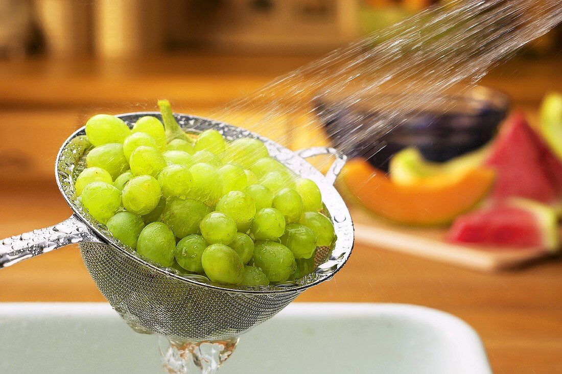 Grüne Weintrauben werden in einem Sieb gewaschen