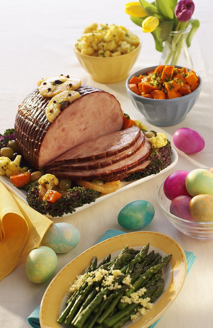 A Baked Ham for Easter with Asparagus and Colorful Easter Eggs
