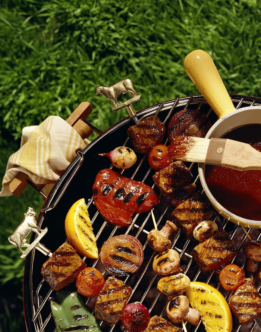 Meat kebabs and vegetables on barbecue; barbecue sauce