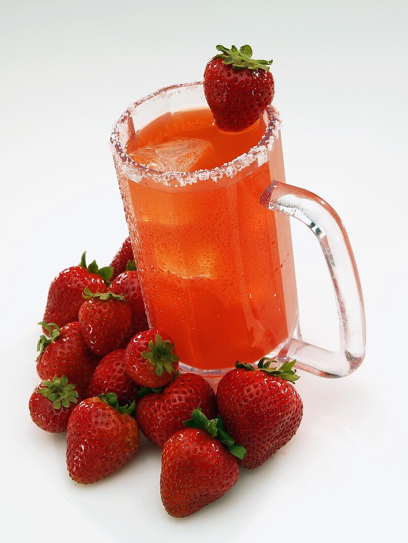 Erdbeer-Margarita in einem Glaskrug und Erdbeeren daneben