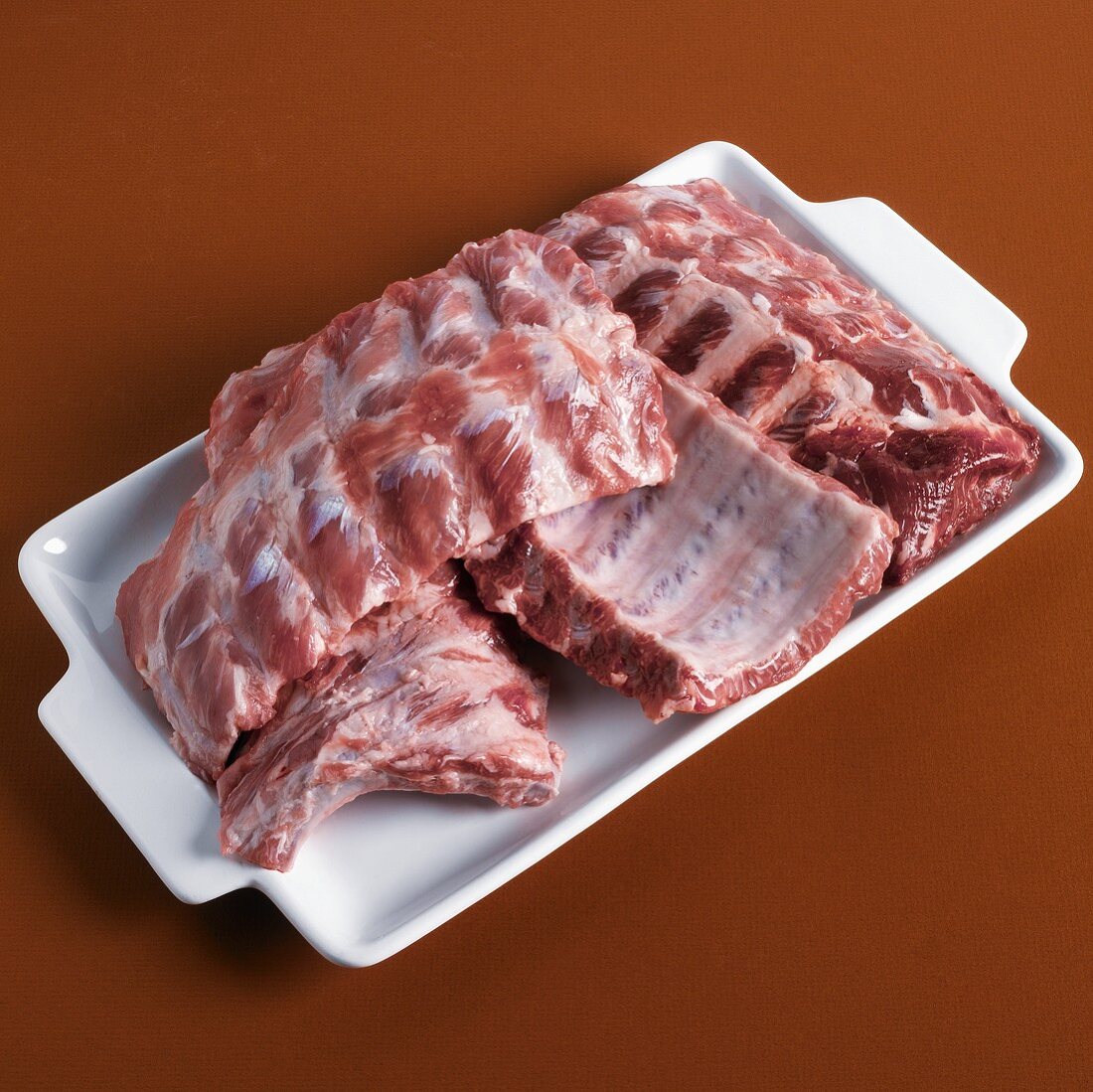 Raw Baby Back Pork Ribs on a White Platter