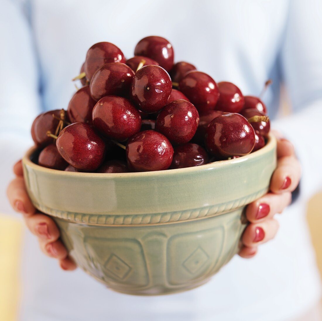 A Woman Holding a Bowl of Green Cherries