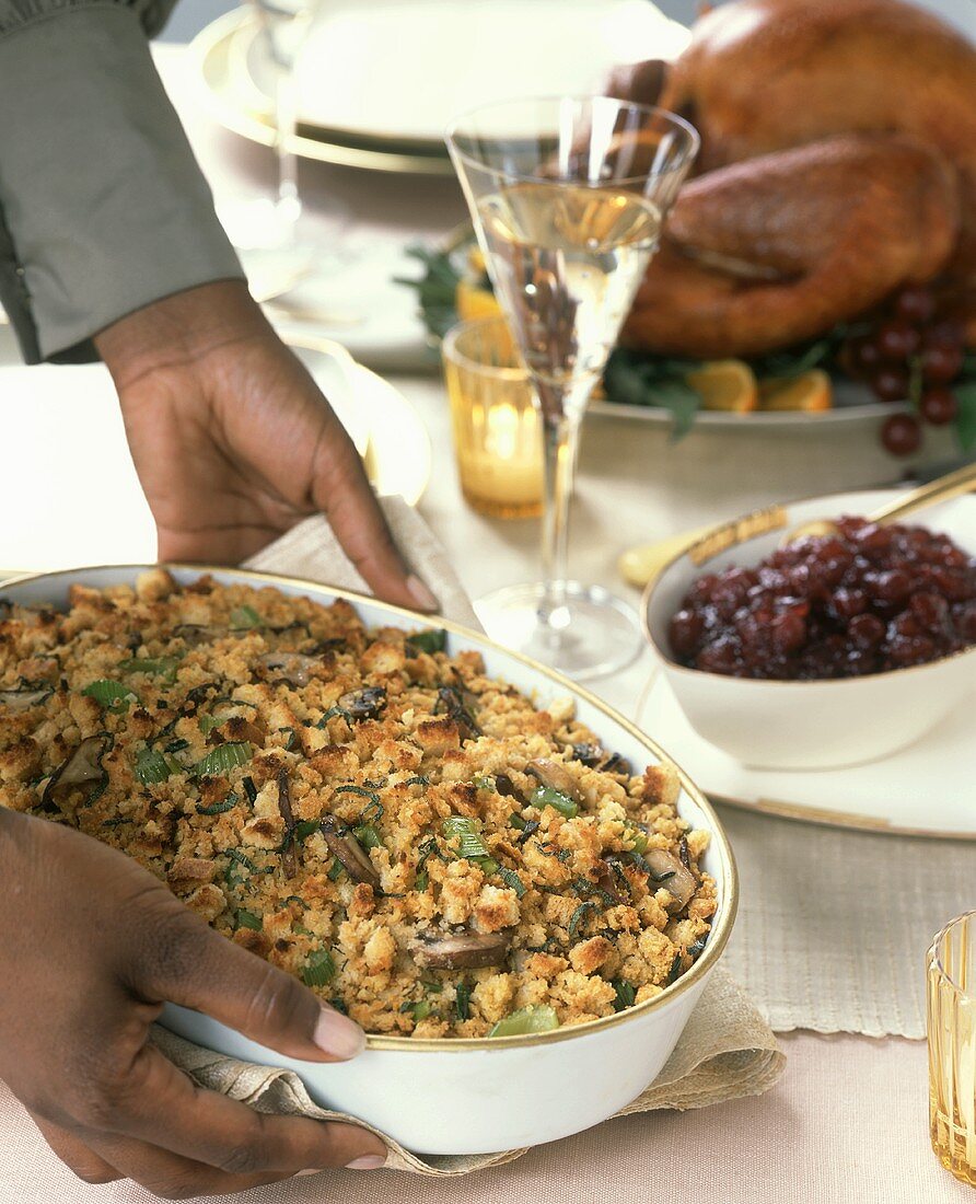 Hands putting a dish of bread stuffing on a table