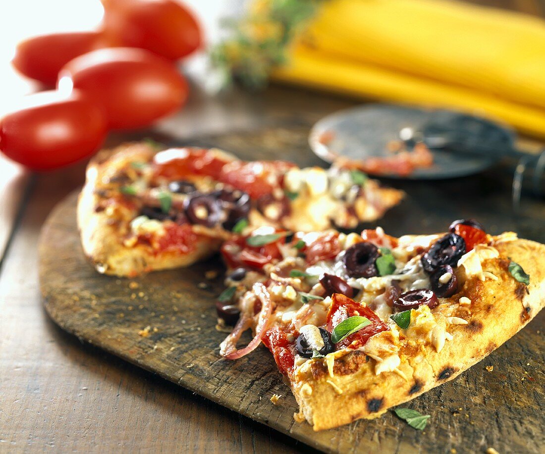 Pizzastücke mit Tomaten, Oliven, Basilikum und Zwiebeln
