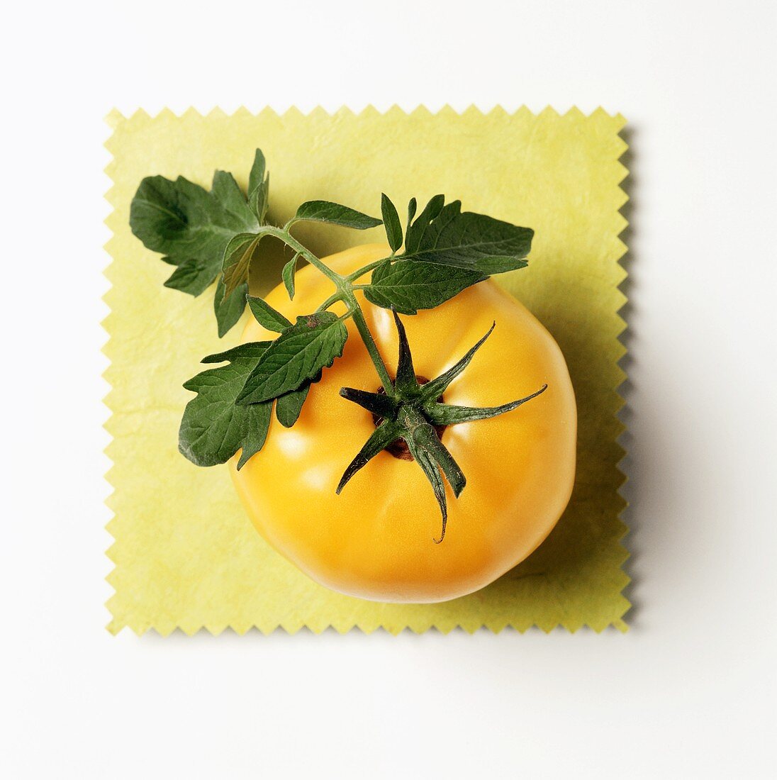 A Yellow Tomato on a Yellow Cloth with Leaves