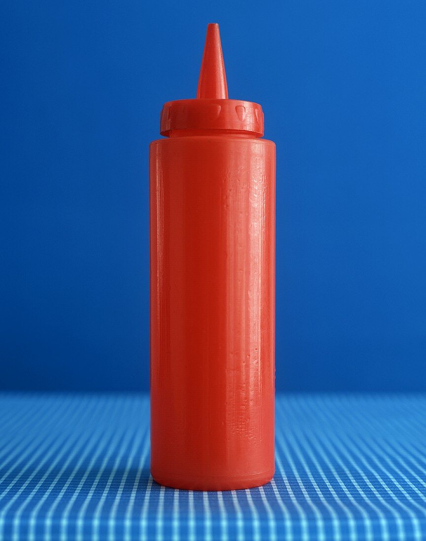 Rote Ketchupflasche vor blauem Hintergrund
