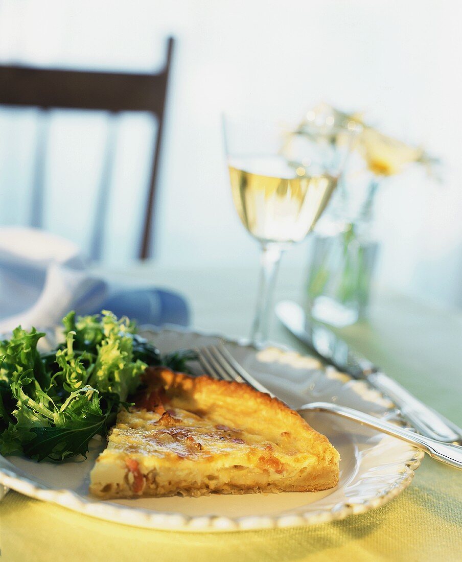 Stück Quiche Lorraine mit Salat und Weißwein