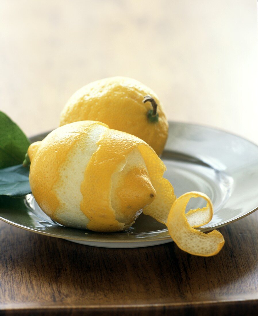 Two Lemons on a Plate; One Peeled