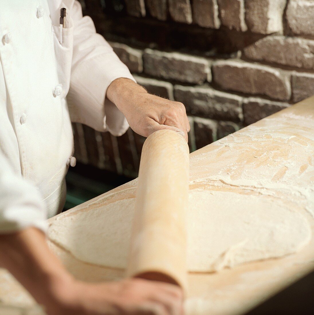 Chef Rolling Dough with a Wooden Rolling Pin