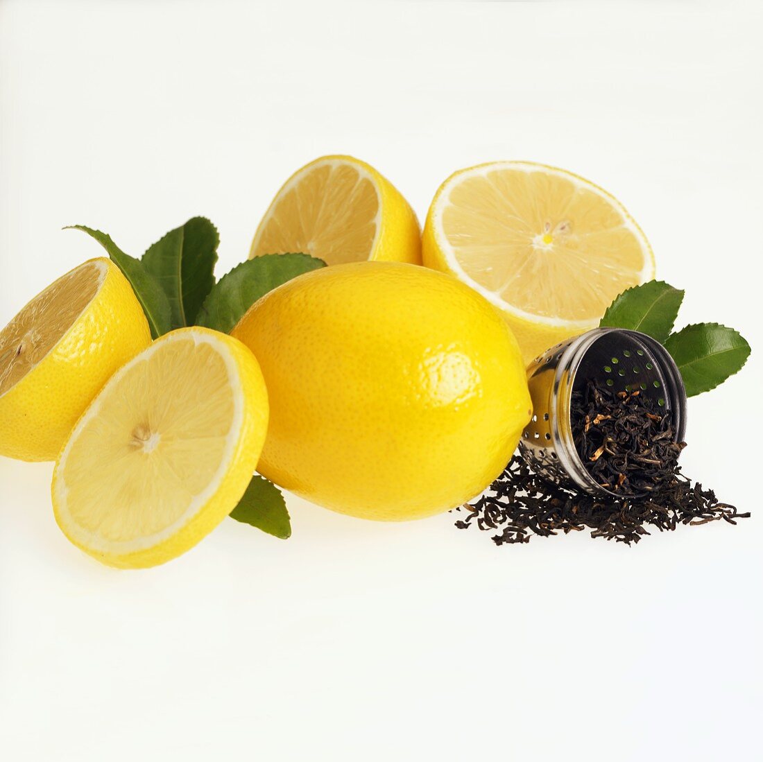 Frische Zitronen und geöffnetes Tee-Ei mit Schwarztee