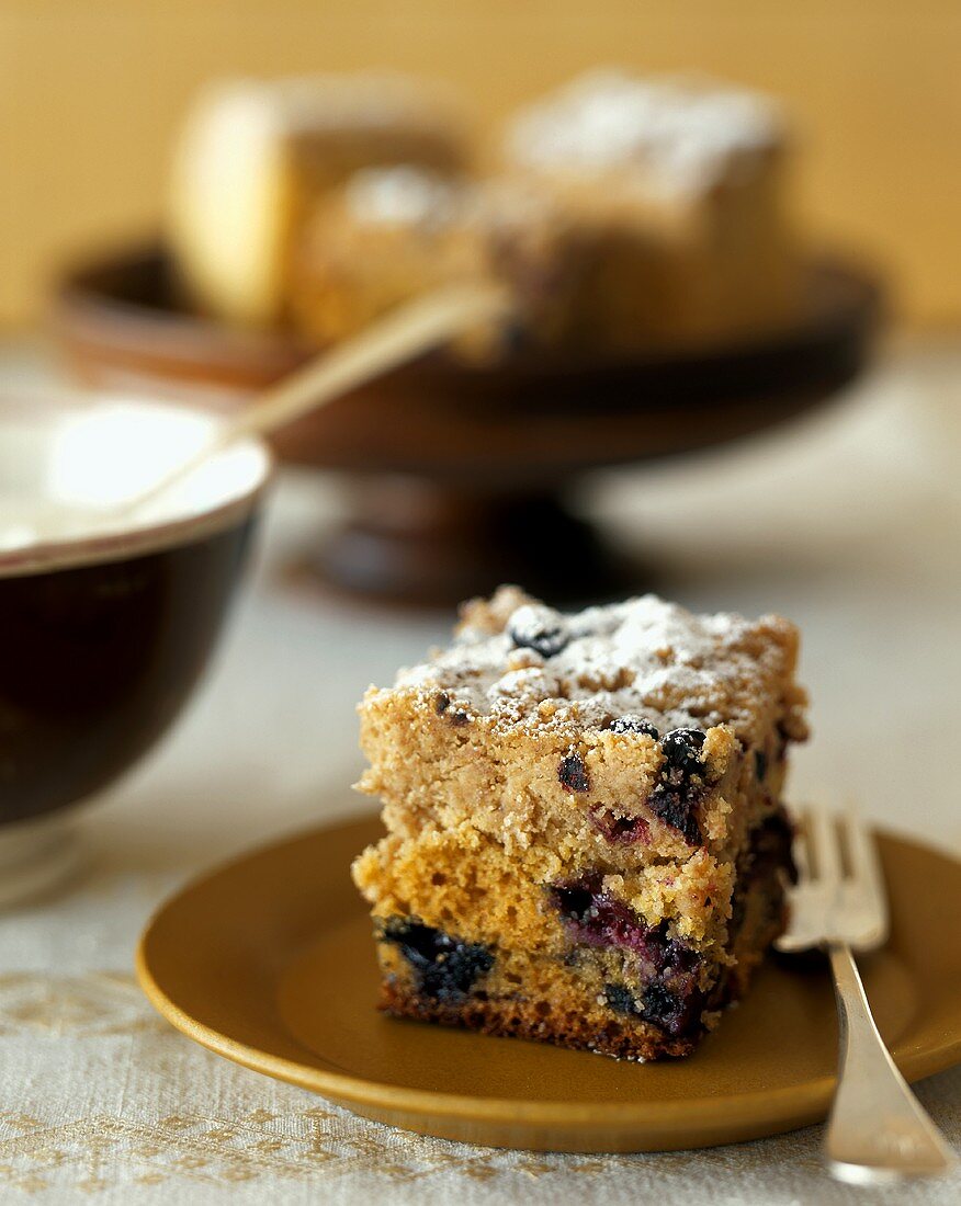 Piece of coffee cake with blueberries and icing sugar