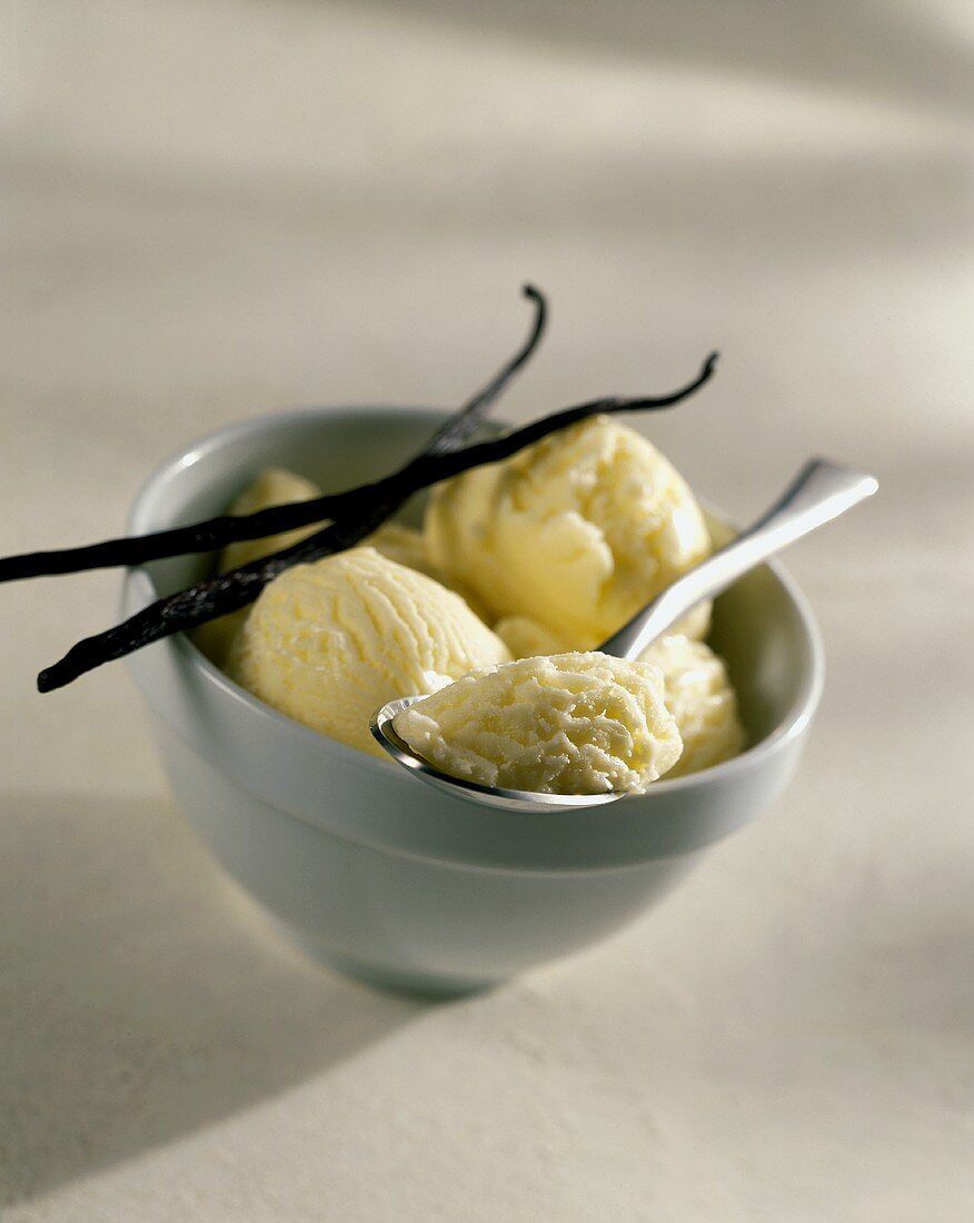 Vanilla ice cream in bowl with spoon and vanilla pods