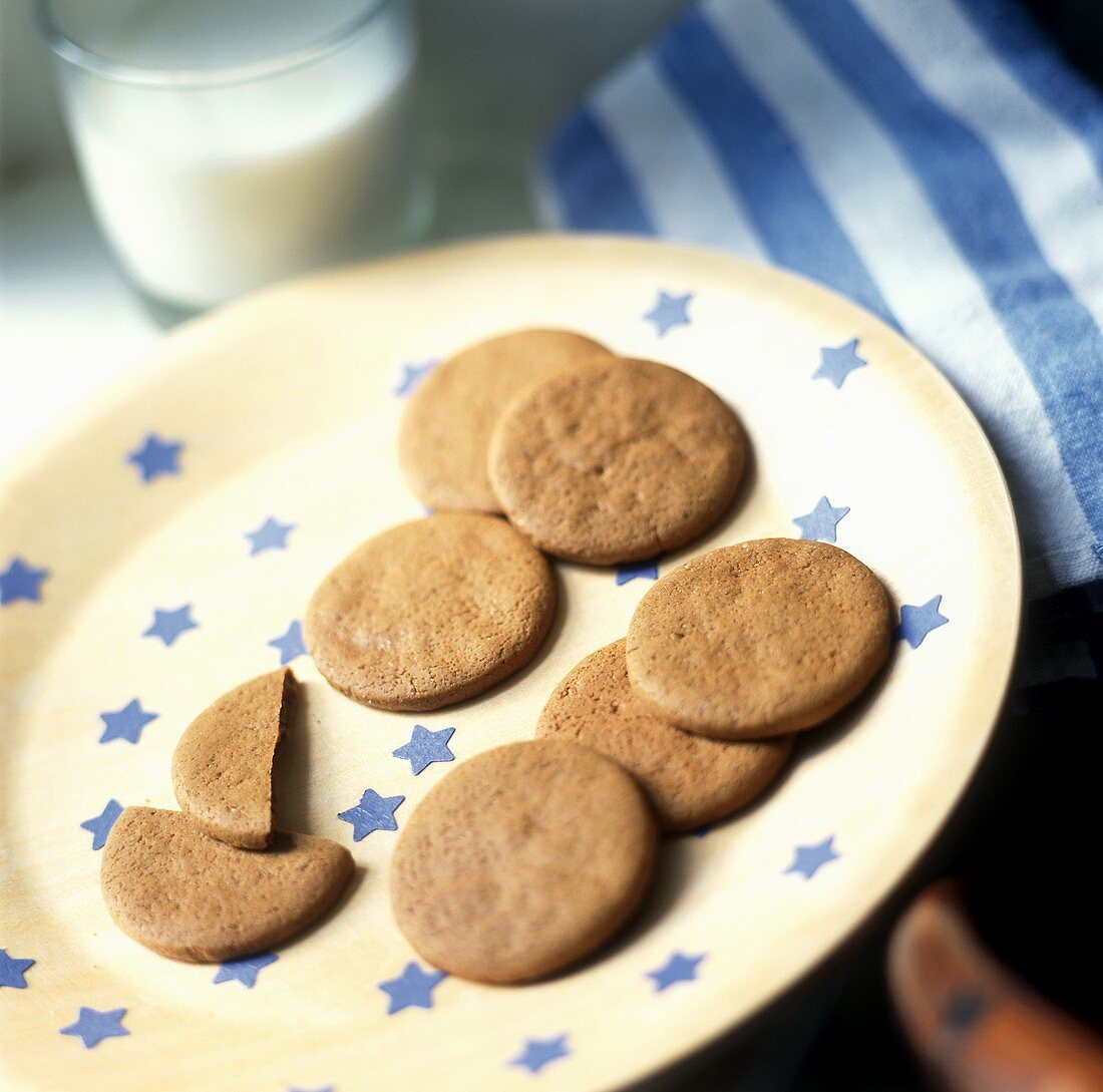 Ginger biscuits on plate with blue stars; glass of milk