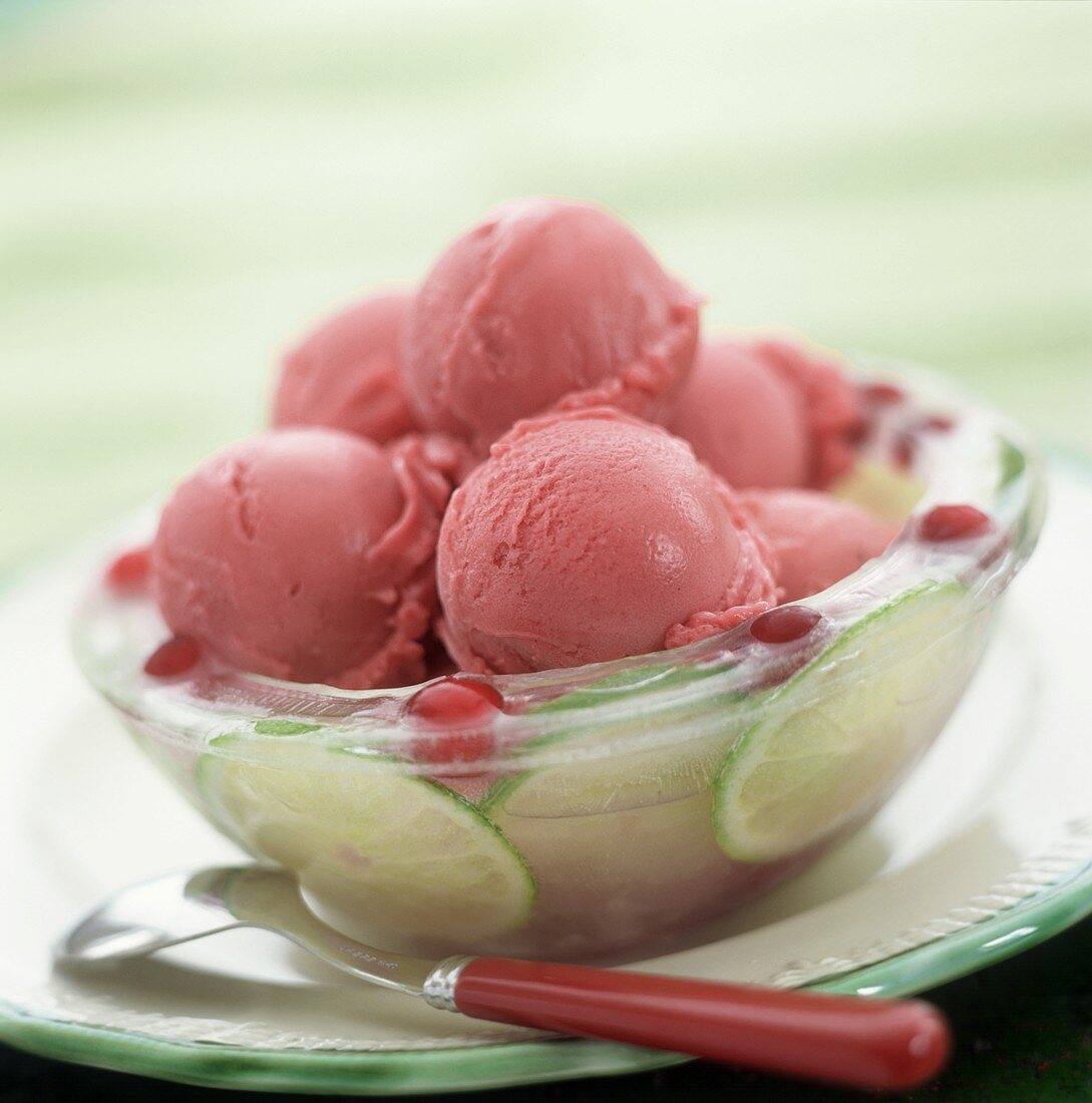 Scoops of raspberry ice cream on lime slices in glass bowl