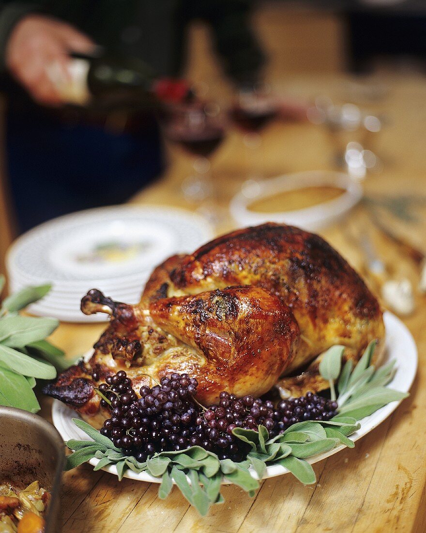 Roasted and Stuffed Turkey with Grapes and Sage on a Table