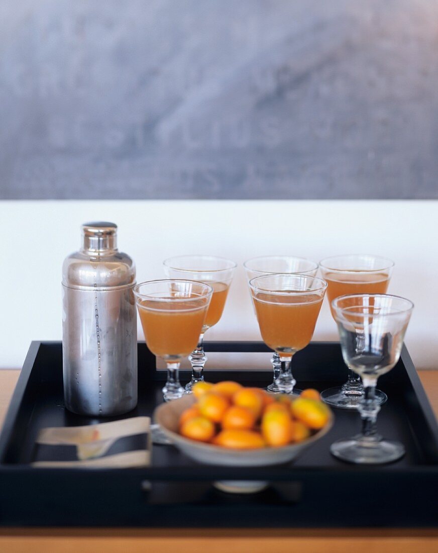 Mehrere Drinks, Cocktailshaker und Schale mit Kumquats