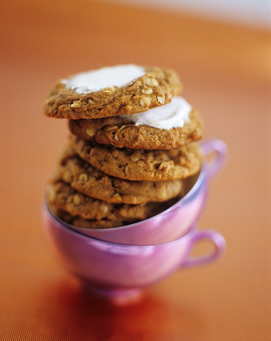 A Stack of Frosted Oatmeal Cookies on Two Purple Tea Cups