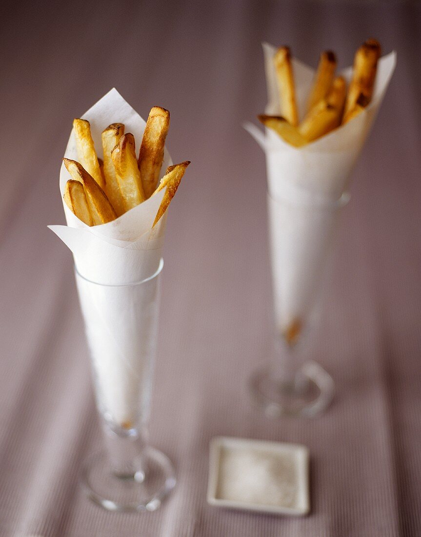 Pommes frites in Papiertüten in zwei Gläsern; Salz