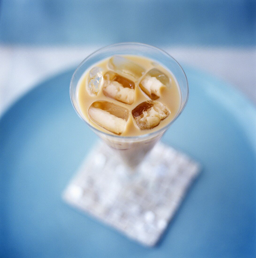 Milchkaffee mit Eiswürfeln im Glas