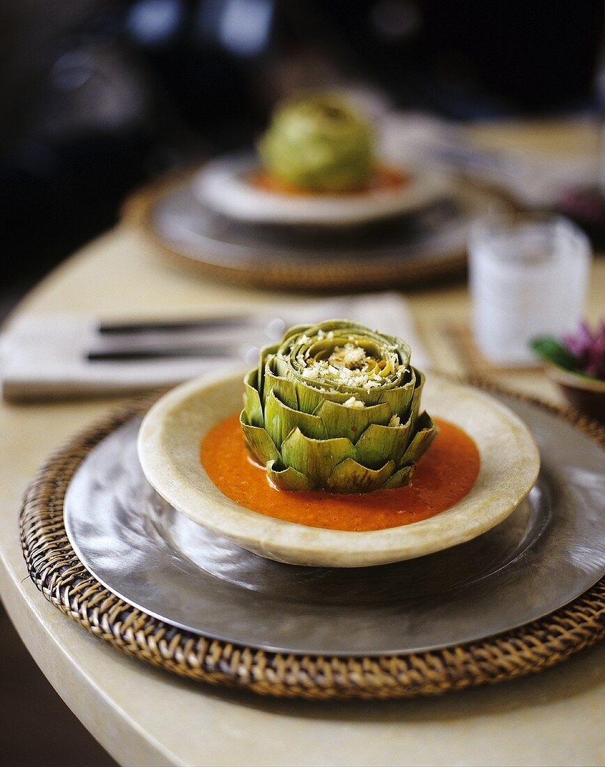 A Table Setting with Cheese Sprinkled Artichokes in Tomato Sauce