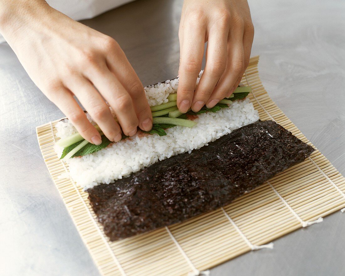 Maki-Sushi zubereiten: Noriblatt mit Reis und Gemüse füllen