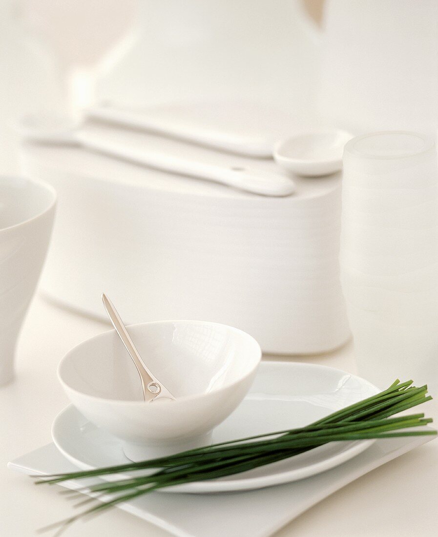 A Bunch of Fresh Chives on a White Plate with a White Bowl and Other Kitchen Items