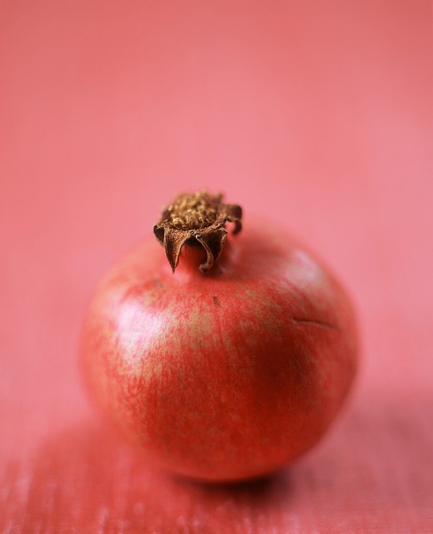A Single Pomegranate on a Pink Background