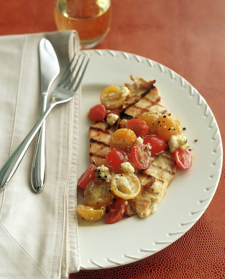 A Grilled Boneless Chicken Breast with Red and Yellow Cherry Tomatoes and Feta Cheese