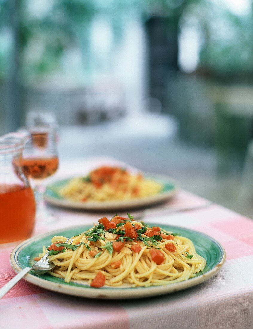 Spaghetti mit Tomaten und Basilikum auf Tisch im Freien