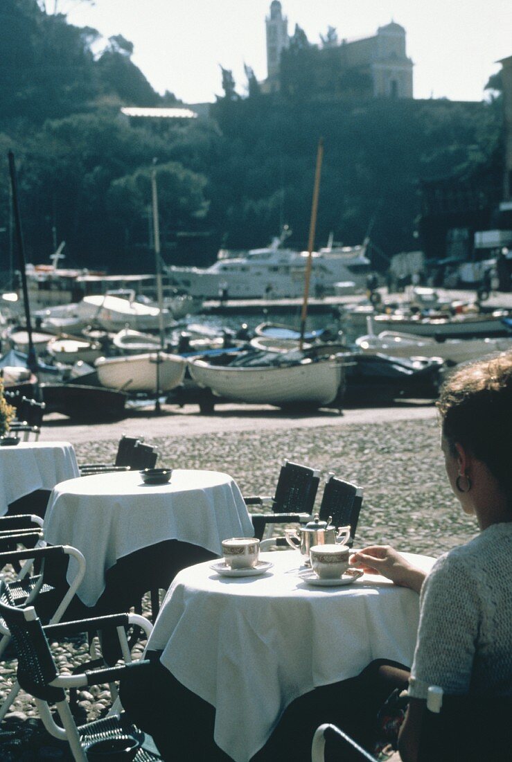 Junge Frau am Tisch eines Cafes an einem Bootshafen