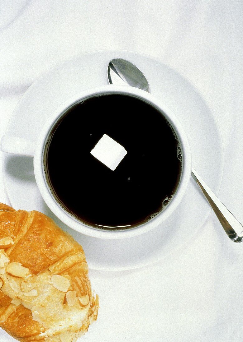 Eine Tasse schwarzer Kaffee, darin ein Zuckerwürfel