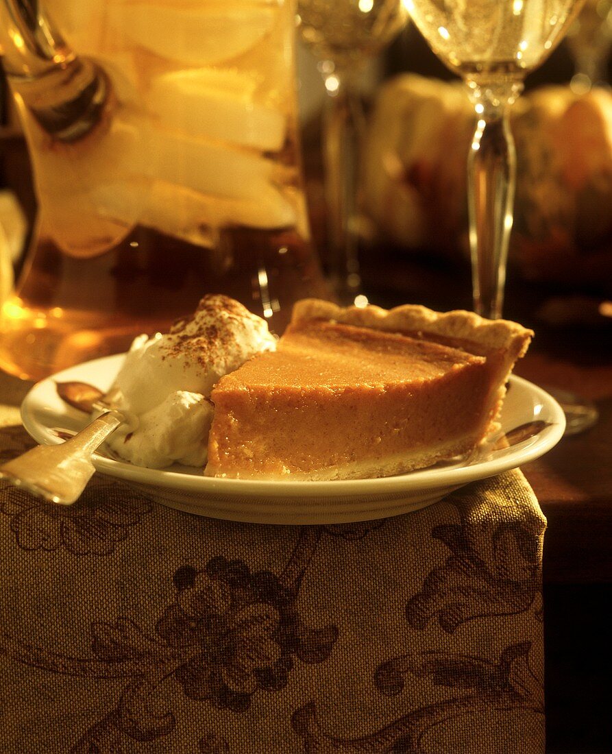 Ein Stück Kürbispie (Pumkin Pie) mit Sahne auf Dessertteller