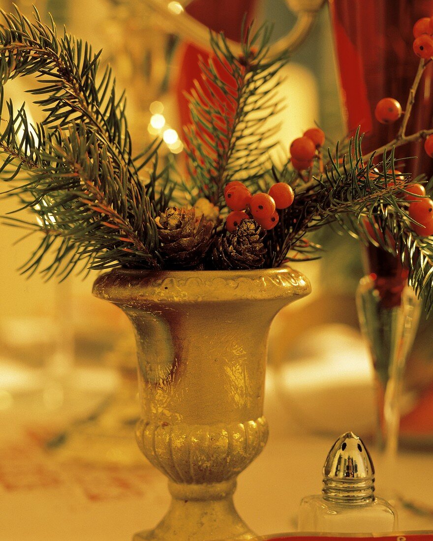 Tannenzweige & Beeren in goldener Vase am Weihnachtstisch