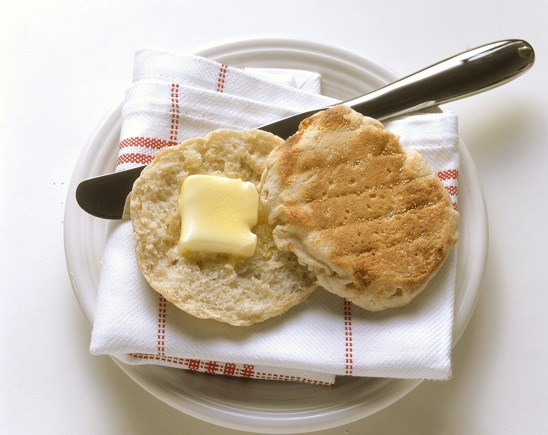 An English muffin with Butter on a Plate