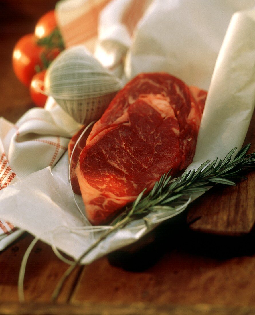 Rib Eye Steak mit Küchengarn & Rosmarinzweig auf Papier