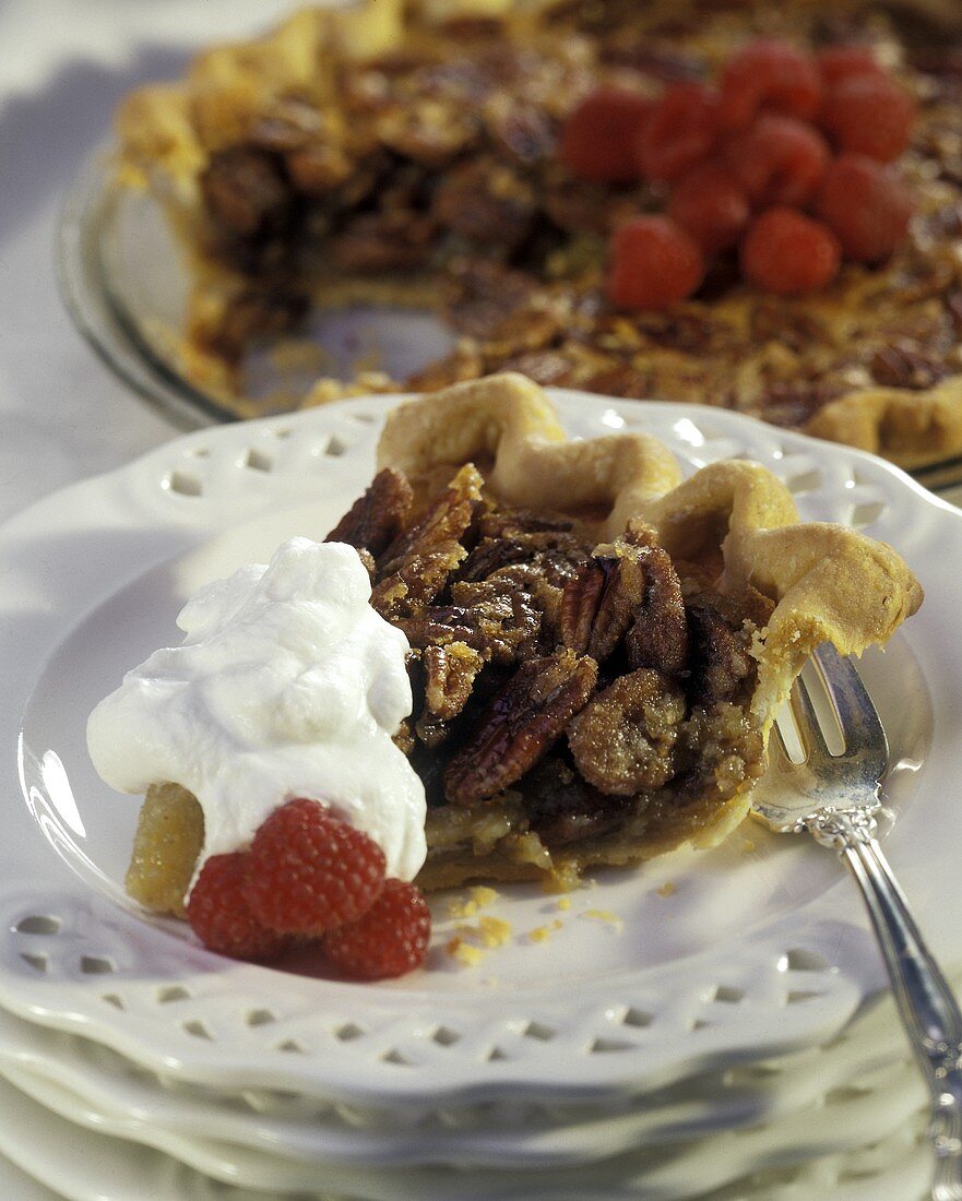 A Slice of Pecan Pie with Whipped Cream and Raspberries