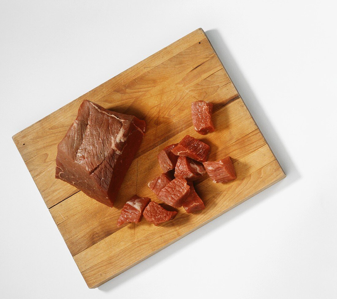 Rindfleisch, im Stück und in Würfel geschnitten auf Holzbrett