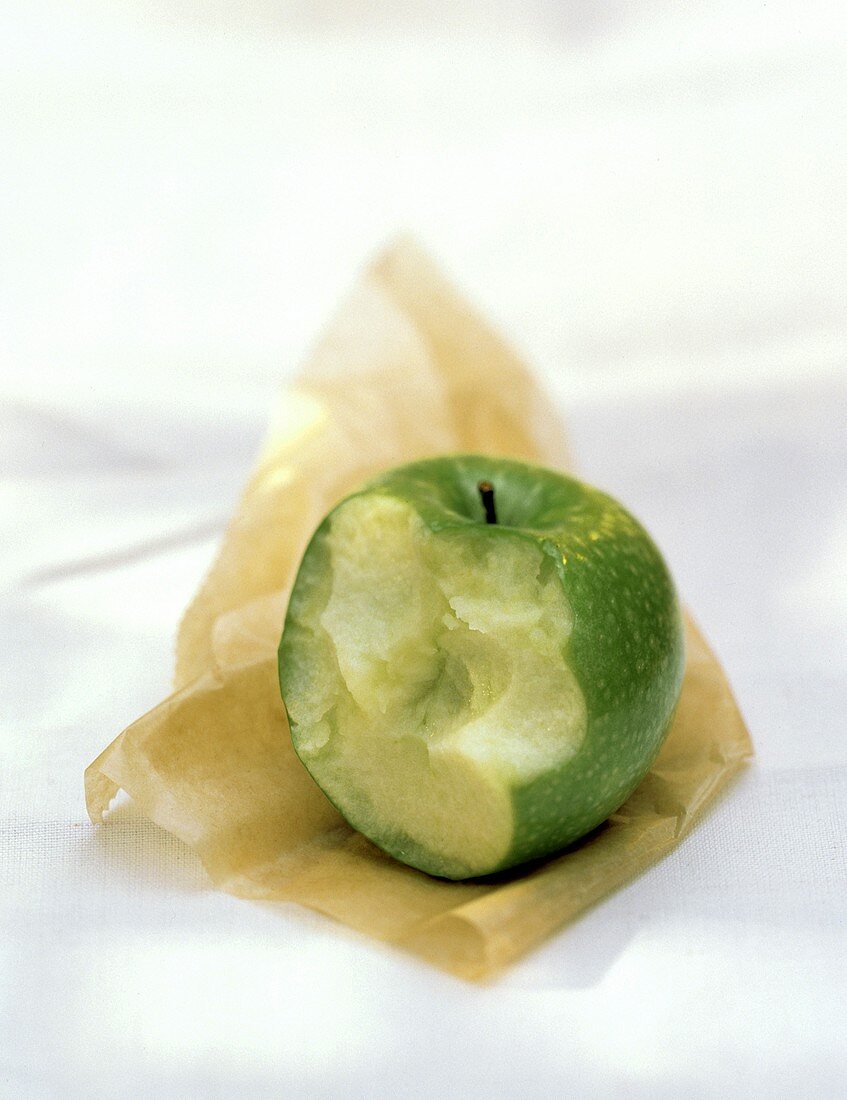 Ein angebissener Granny Smith Apfel auf Papier