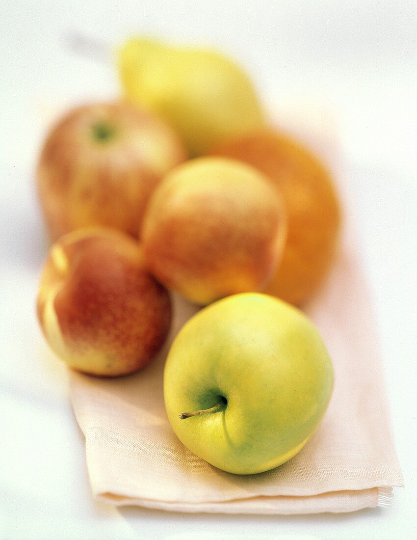 Ein Golden Delicious Apfel vor Obst (unscharf im Hintergrund)