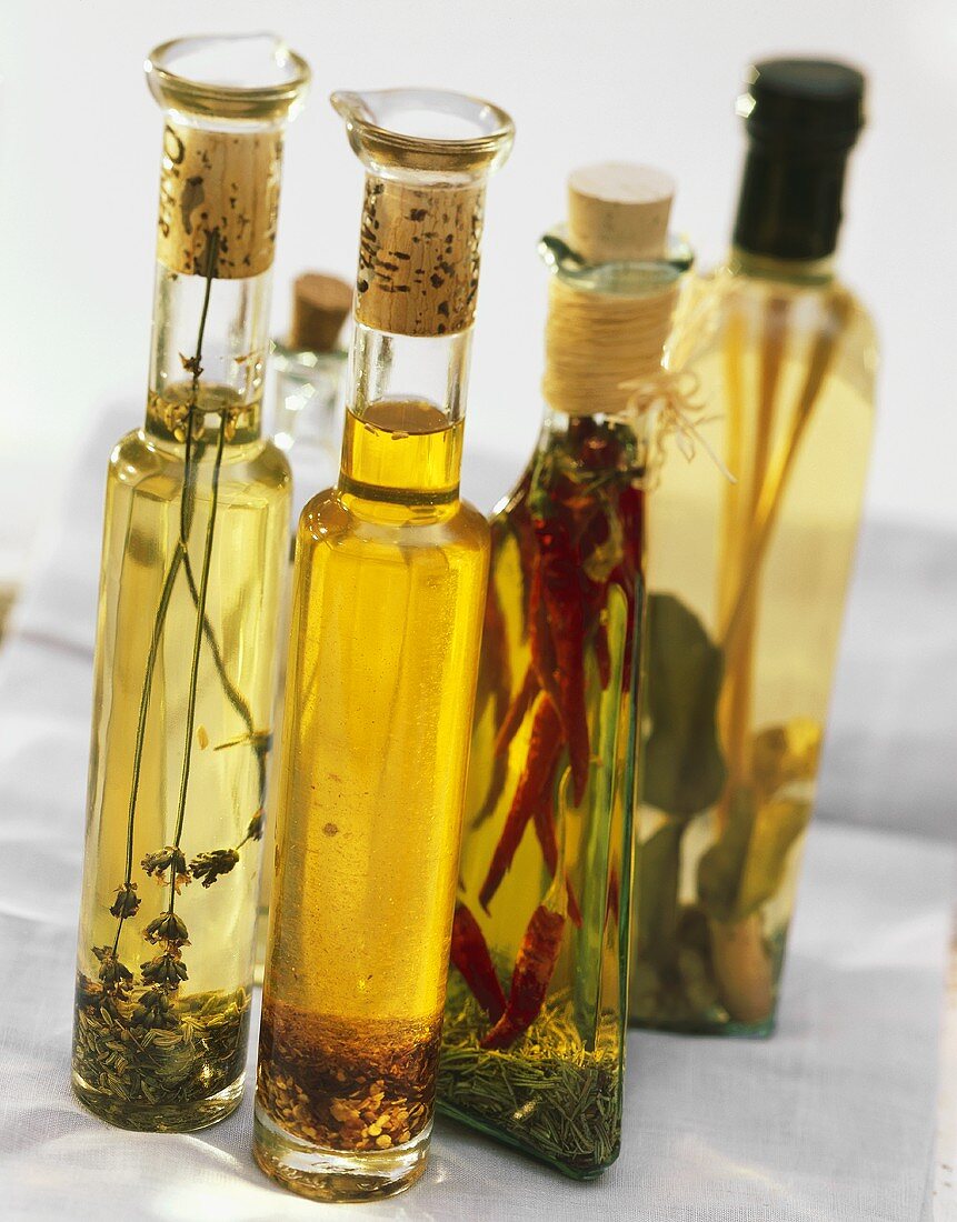 Vier verschiedene Kräuter- und Gewürzöle in Flaschen
