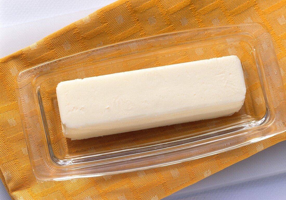 Ein Stück Butter in Glasgeschirr auf Stoffserviette