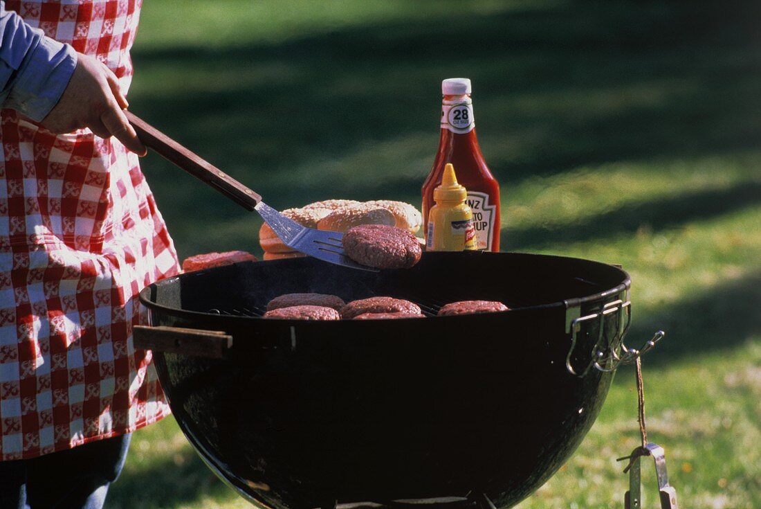 Mann grillt Hamburger im Freien