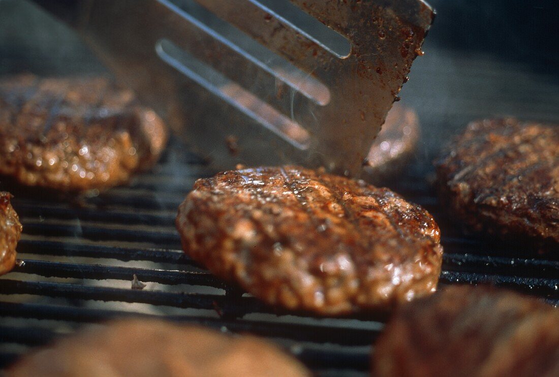 Gegrillte Frikadellen auf dem Grill mit Bratenwender