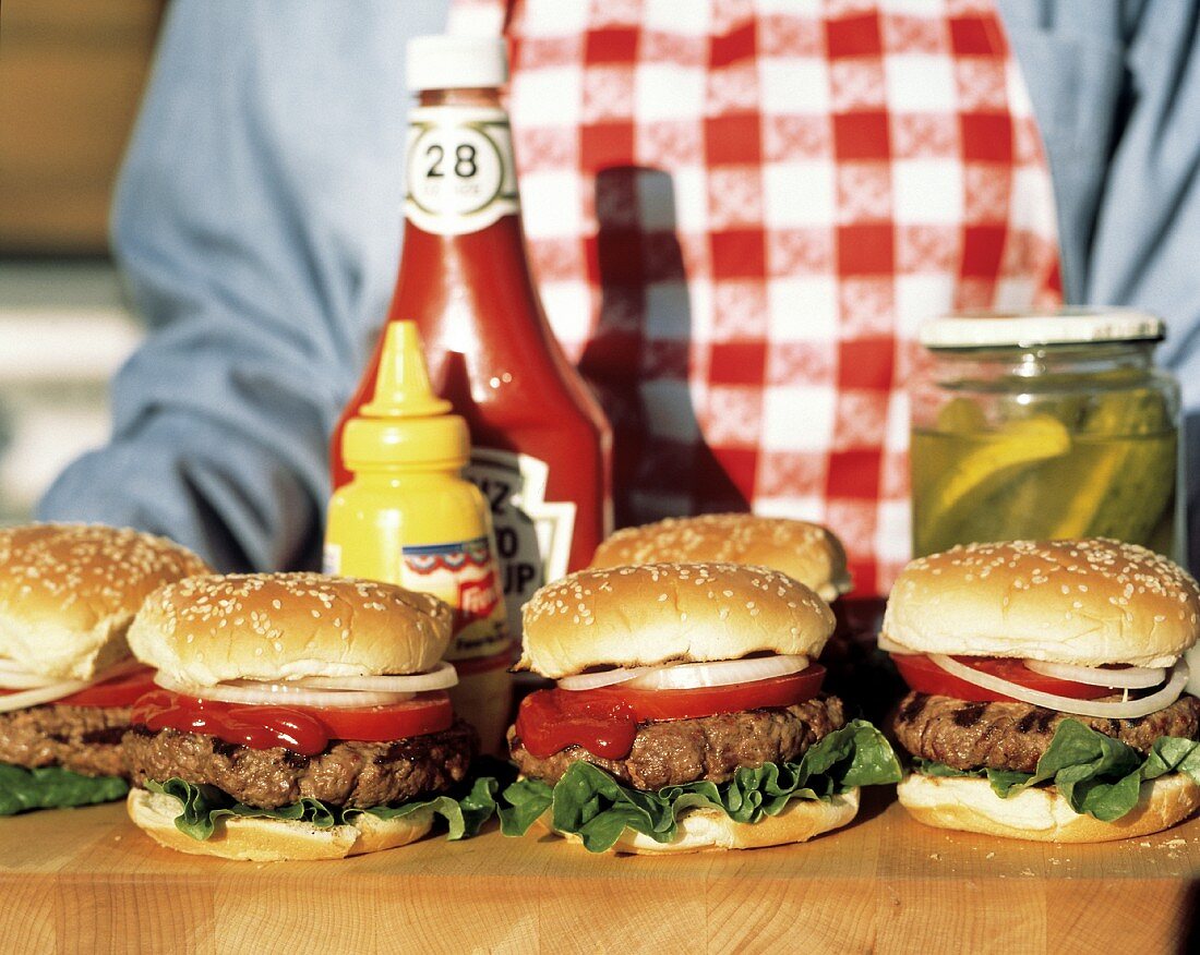 Hamburger auf Holzbrett mit Ketchup, Senf, Gewürzgurken