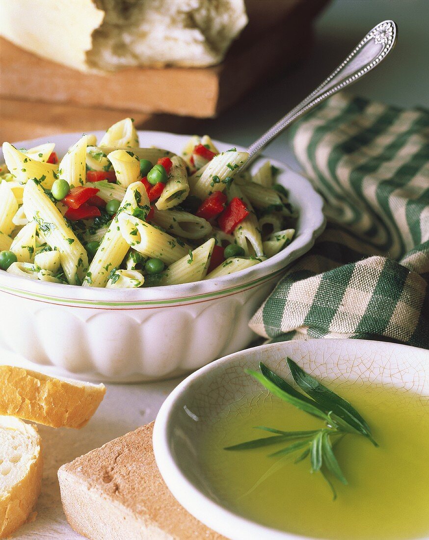 Penne-Gemüse-Salat in Schüssel und ein Schälchen mit Dressing