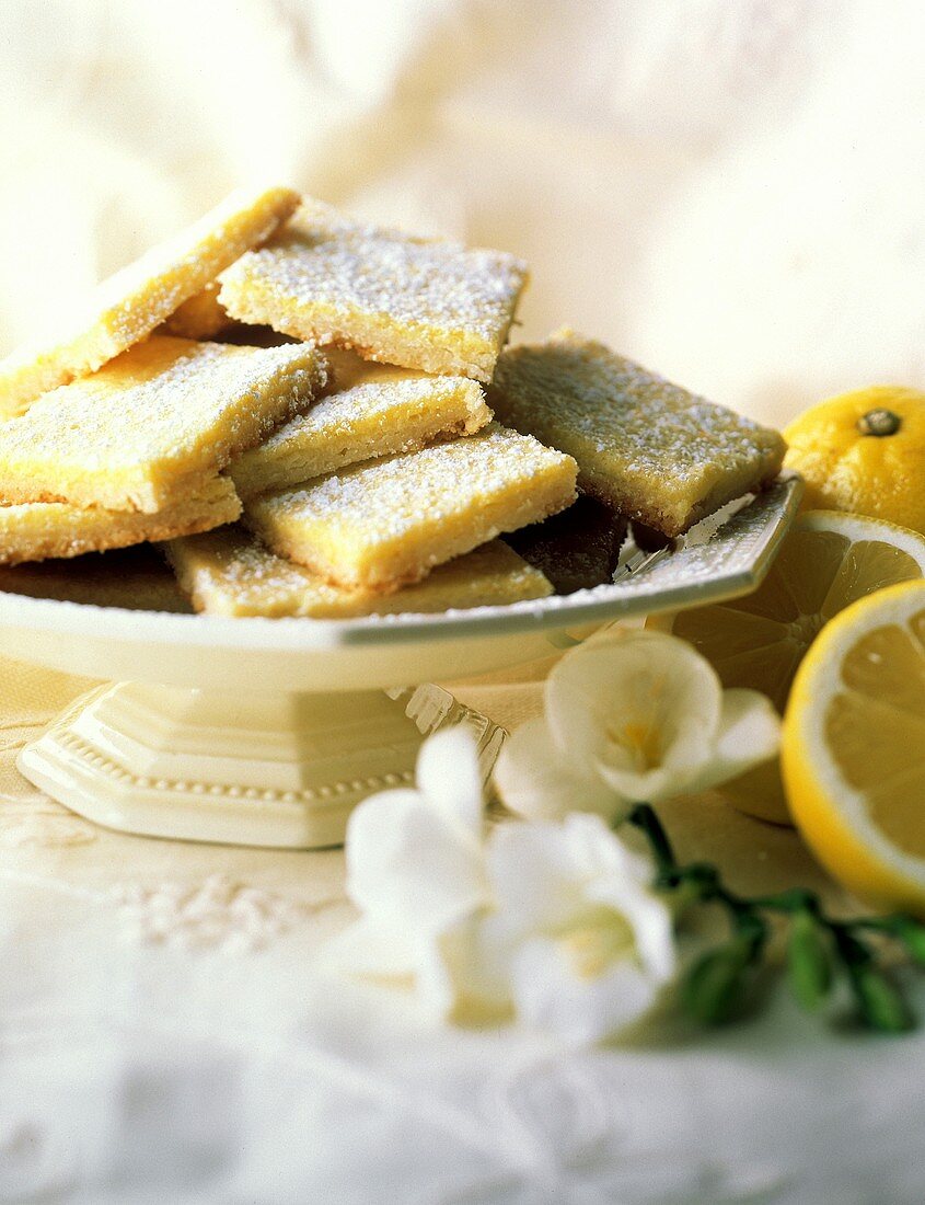 Flache Zitronenkuchen-Quadrate mit Puderzucker auf Platte