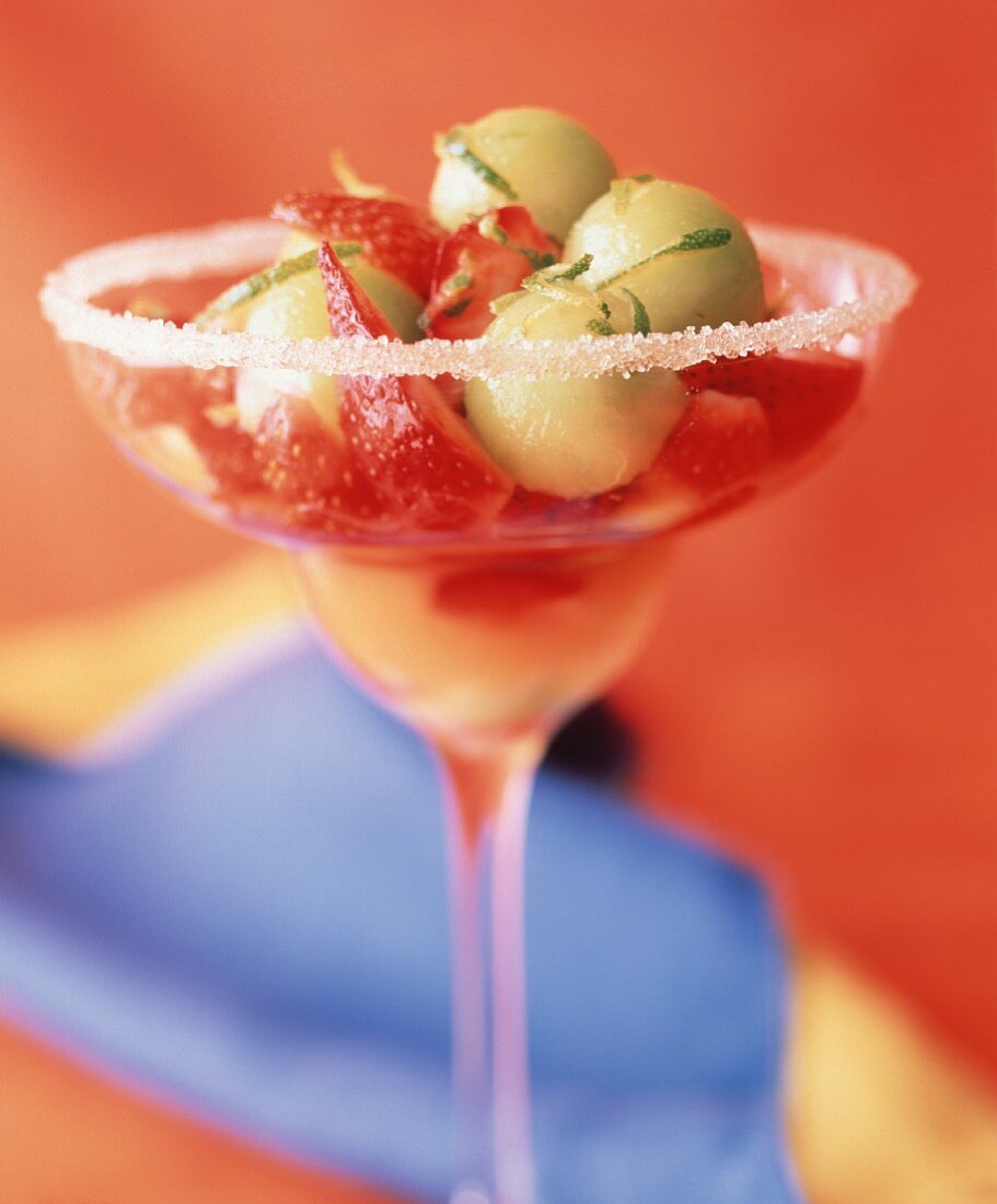 Fruchtsalat mit Erdbeeren & Melonenkugeln in dekorativem Glas