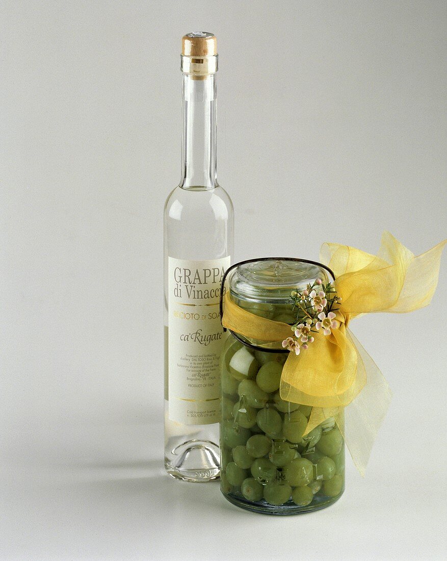 Eine Flasche Grappa & grüne Trauben im Glas als Geschenk