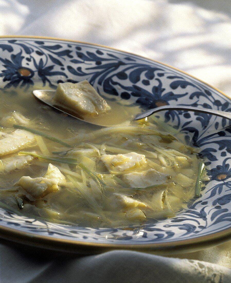 Fischsuppe mit Lauch im Suppenteller mit Löffel